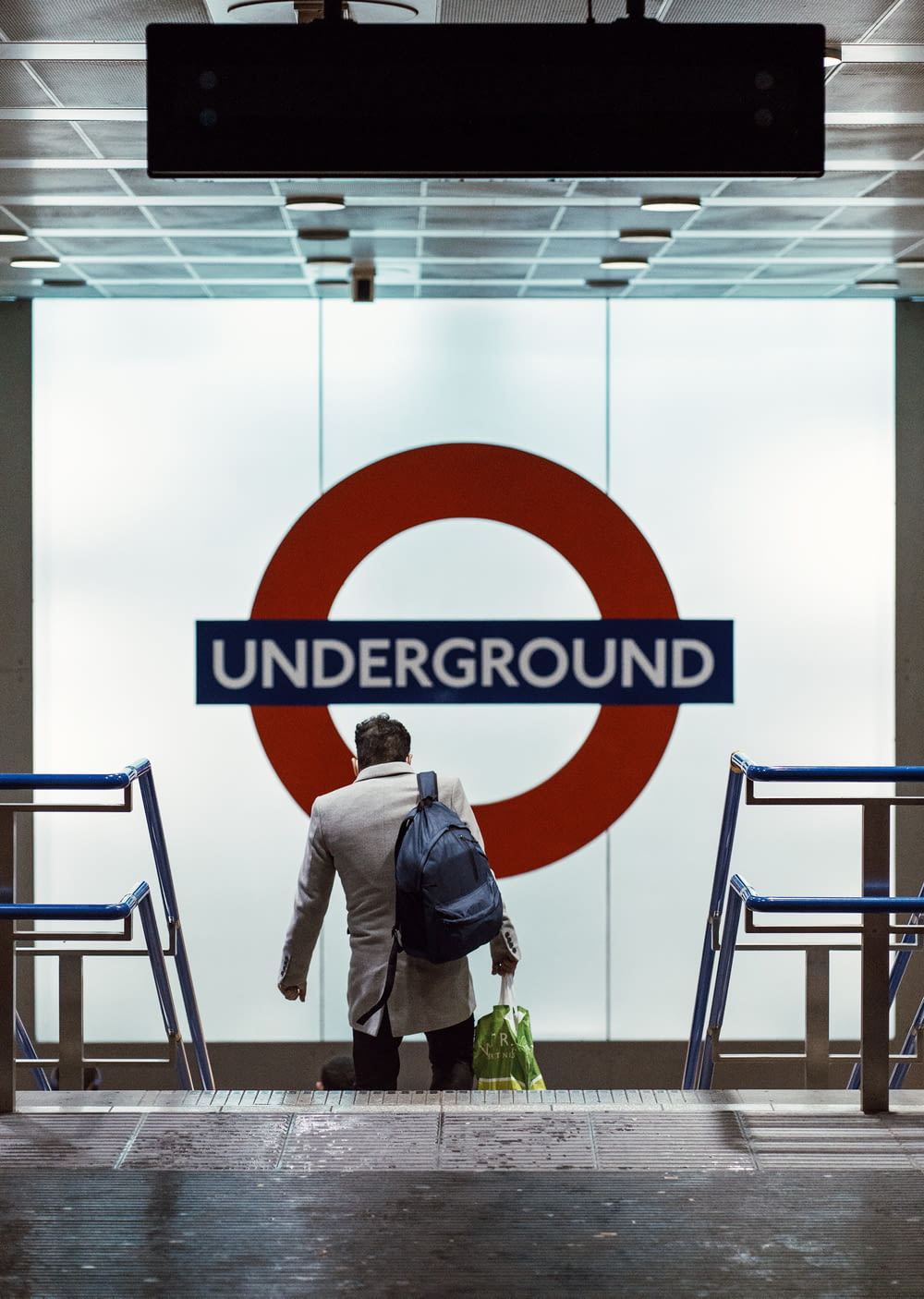 a man with a backpack is standing in front of a underground sign