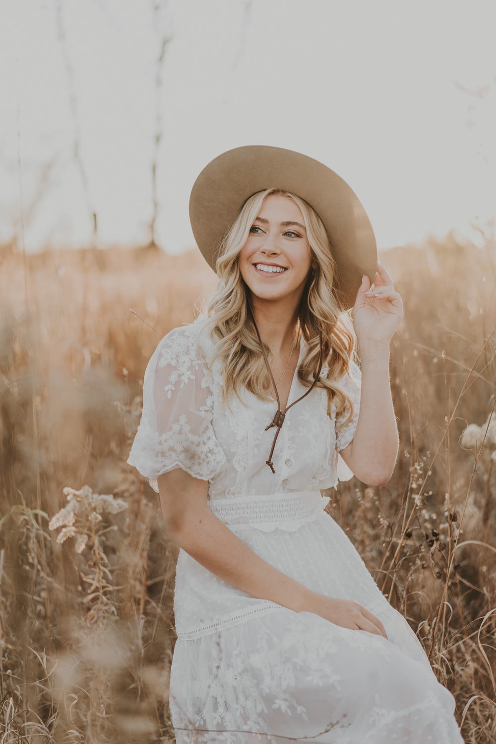 a woman in a hat sitting in a field
