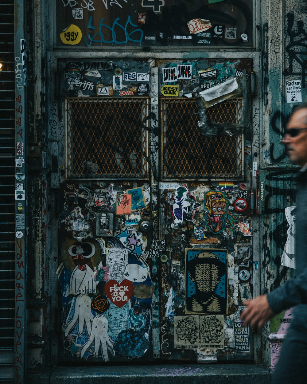a man walking past a door covered in stickers