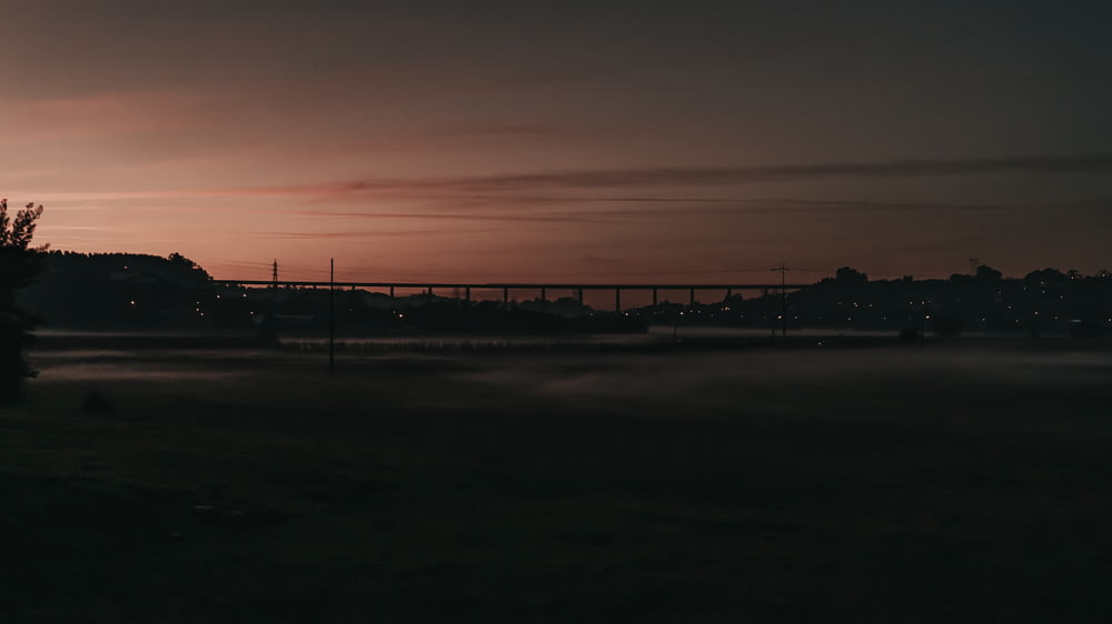 a foggy field with a bridge in the distance