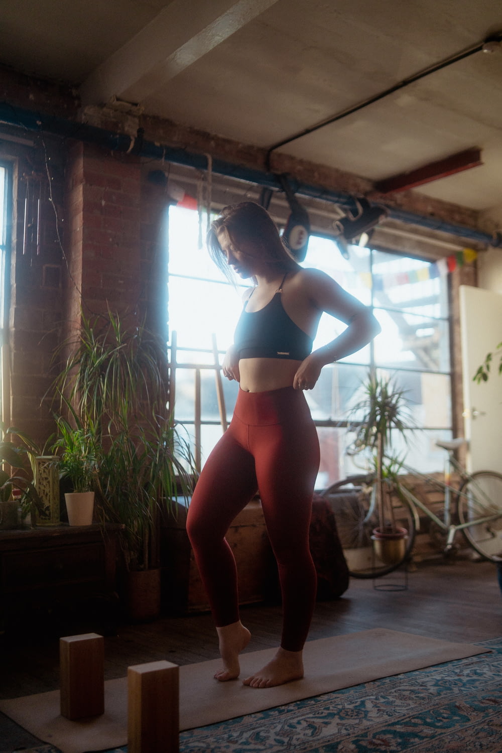 a woman standing on a yoga mat in front of a window