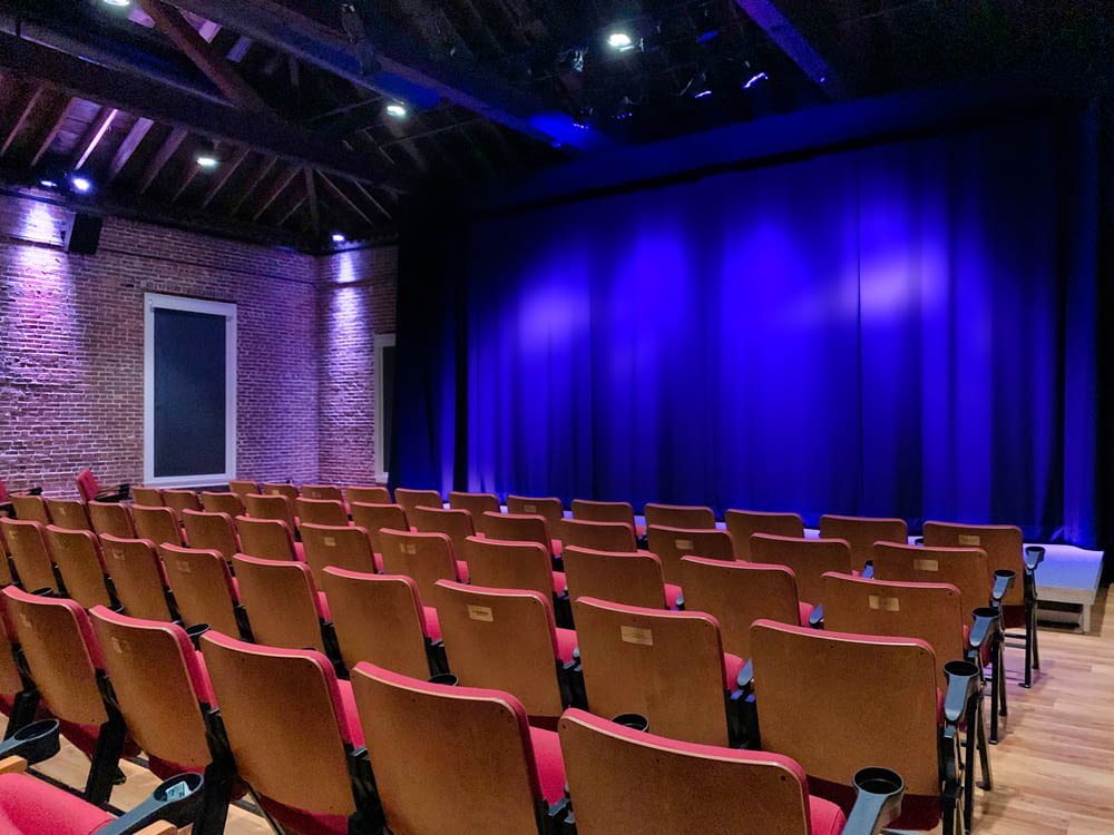 an empty auditorium with red seats and a blue curtain