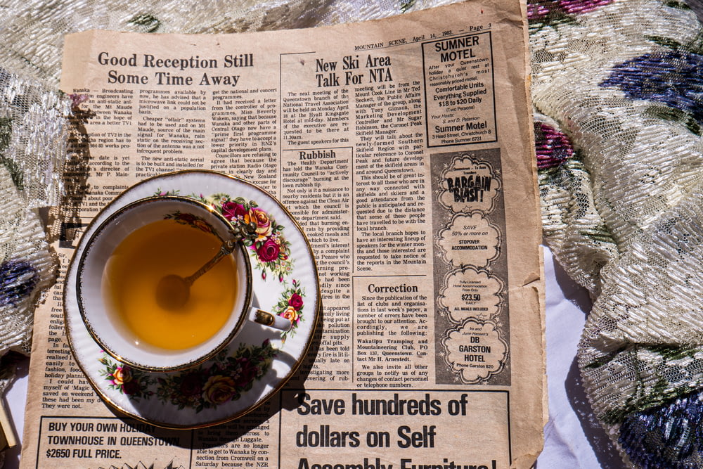 a cup of tea sitting on top of a newspaper