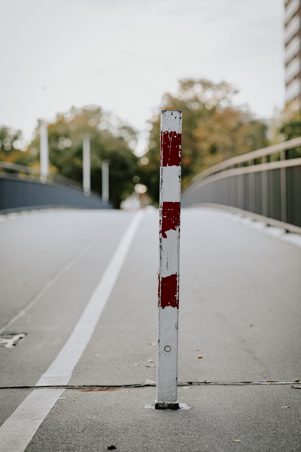 a red and white pole sitting on the side of a road