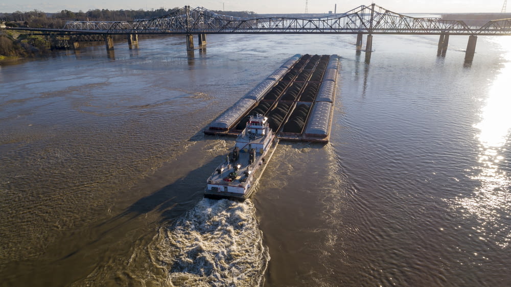 a barge traveling down a river next to a bridge