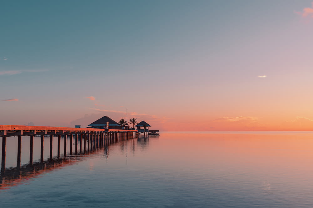a long pier stretches out into the ocean at sunset