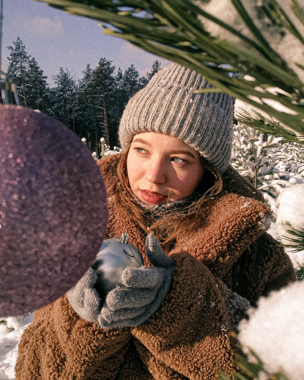 a woman in a brown coat holding a purple ornament