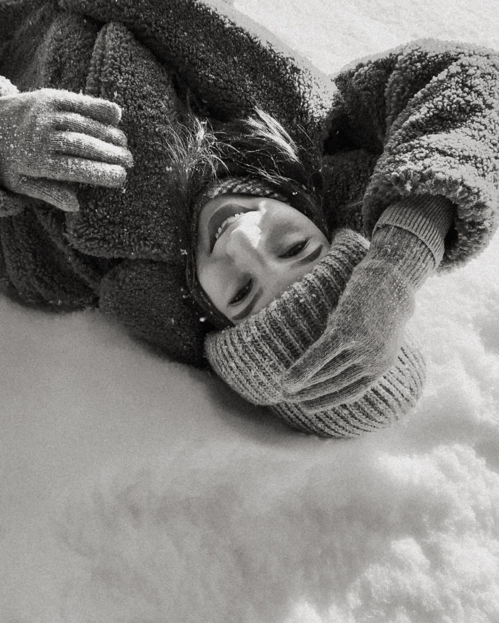 a young child laying in the snow wearing a hat