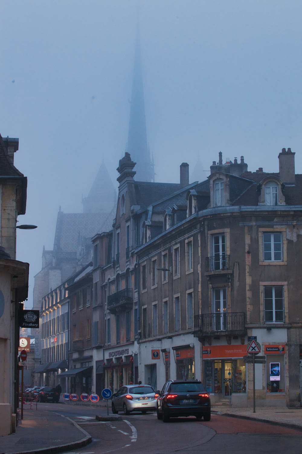 a foggy city street with cars parked on the side of the road