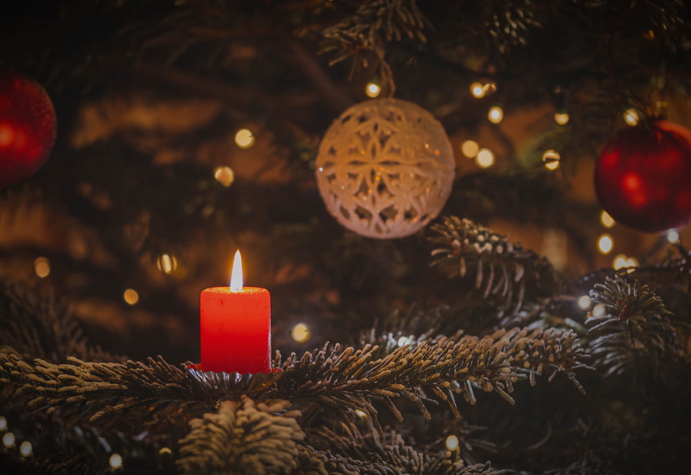 uma vela acesa sentada em cima de uma árvore de Natal
