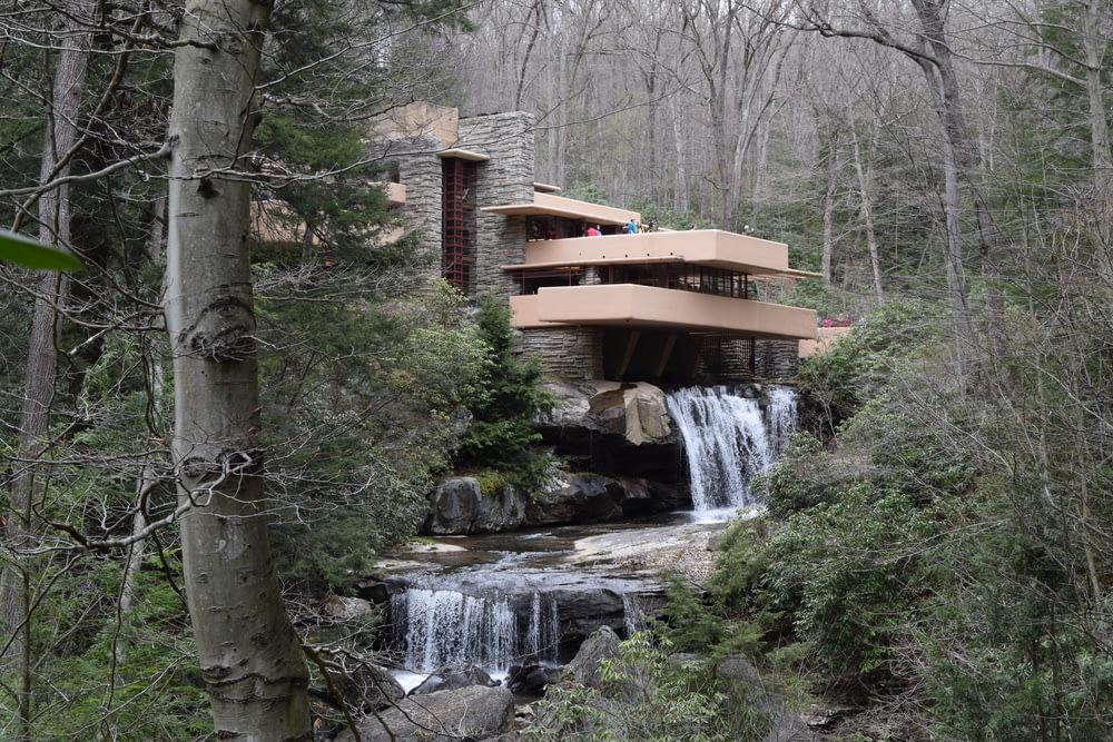 a house in the woods with a waterfall