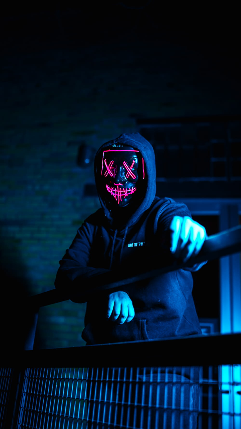 a person wearing a neon mask standing in the dark