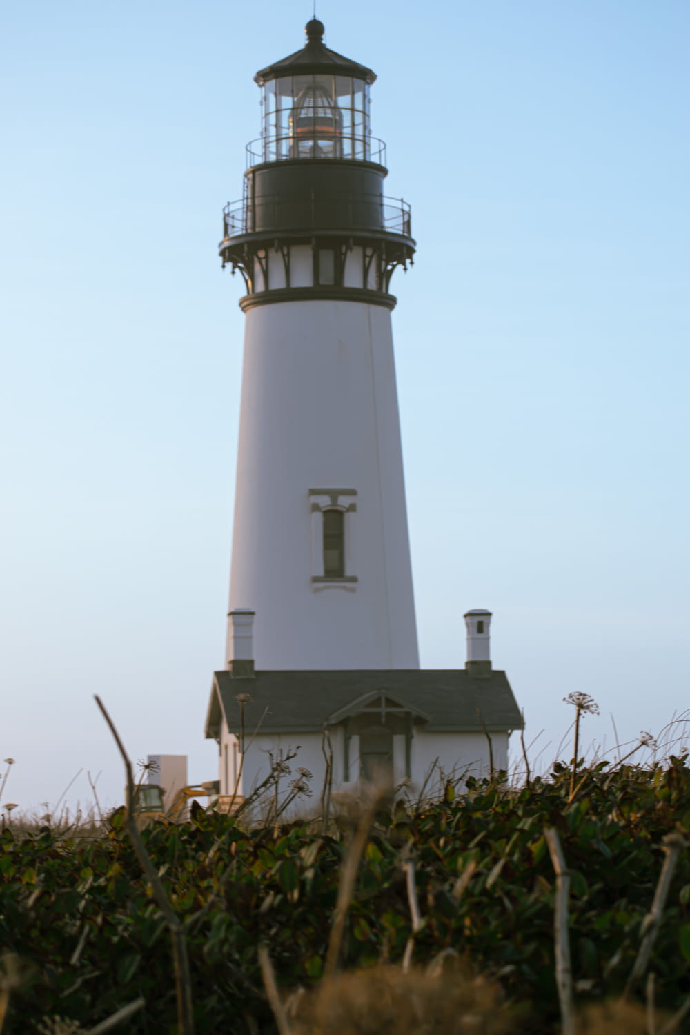 a white lighthouse with a black top on a clear day
