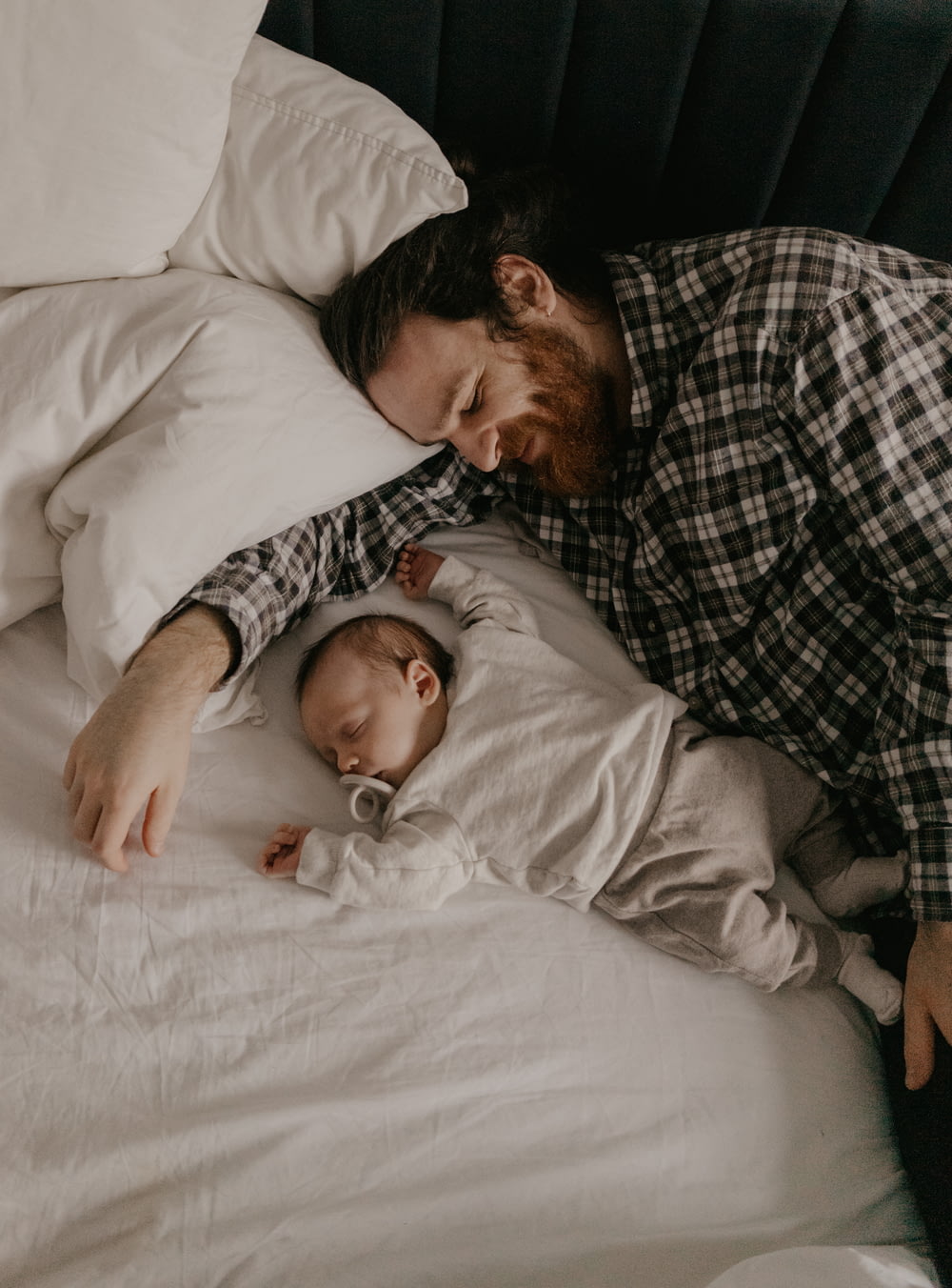 a man laying in bed with a sleeping baby