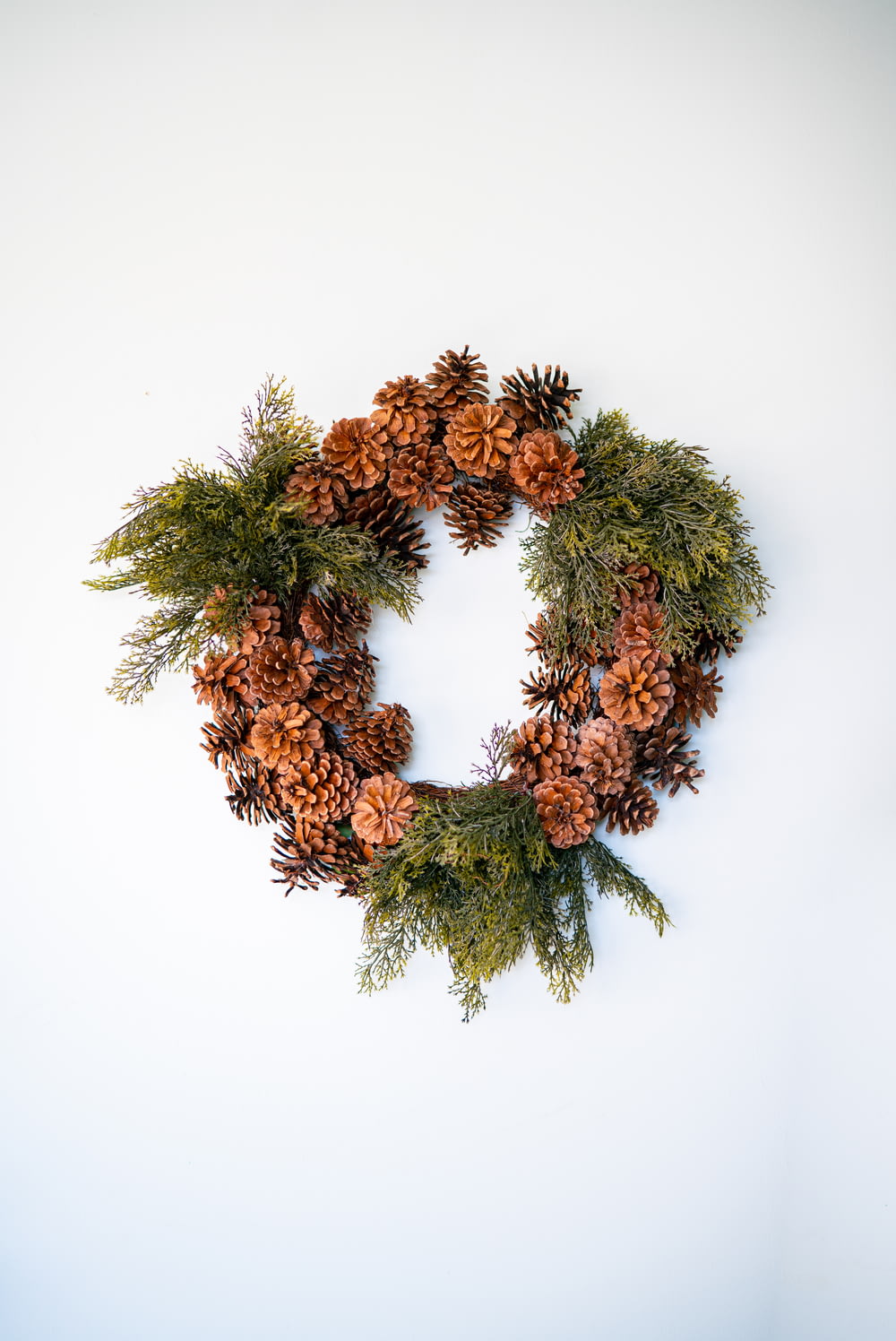 a wreath made of pine cones and evergreen branches