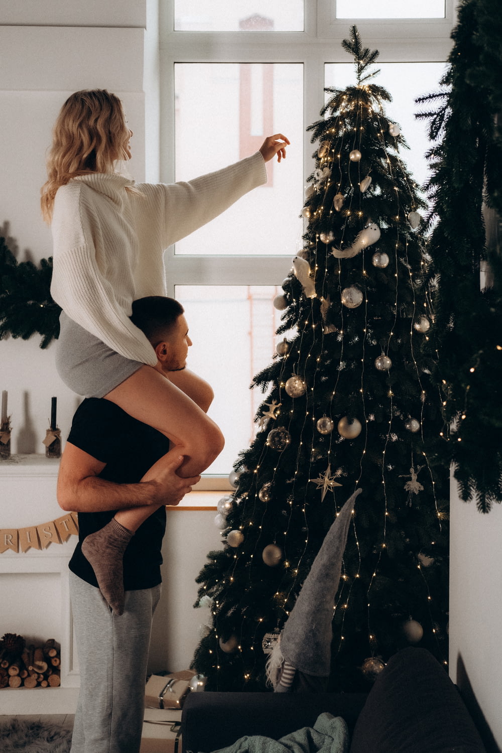a woman holding a man in front of a christmas tree