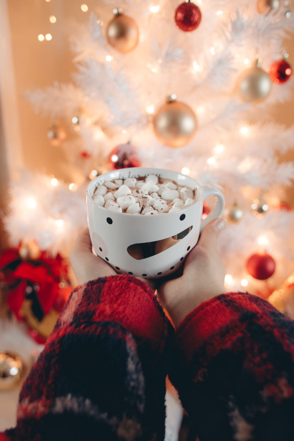 a person holding a bowl of popcorn in front of a christmas tree