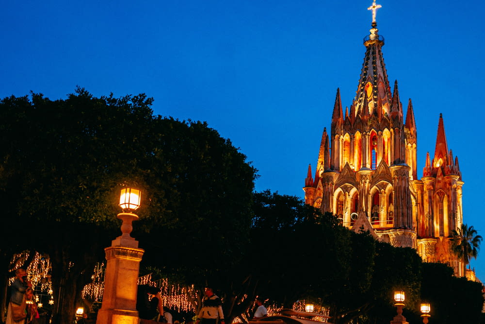 a large cathedral lit up at night with people walking around