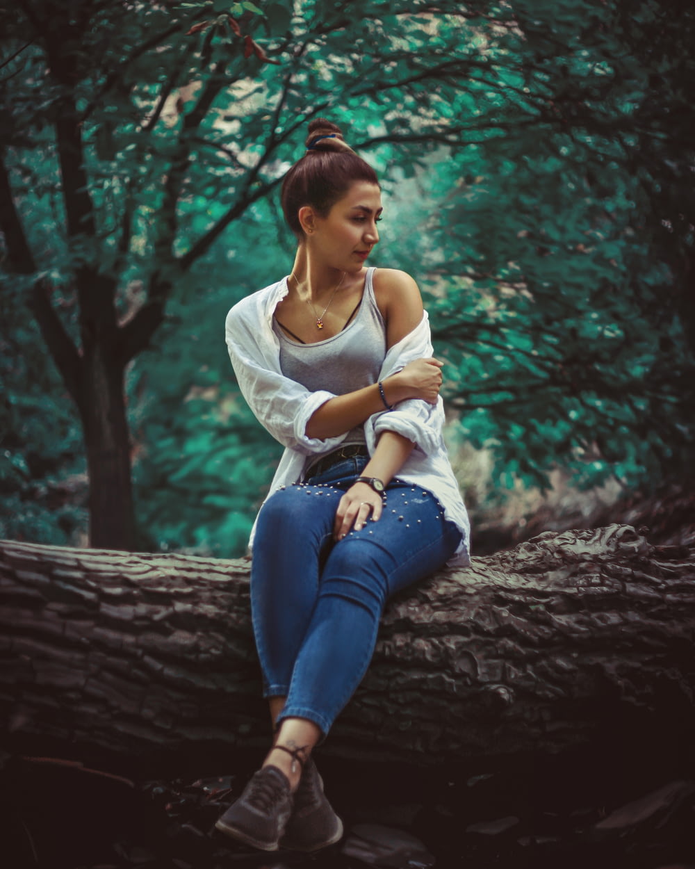 Eine Frau sitzt auf einem Baumstamm im Wald