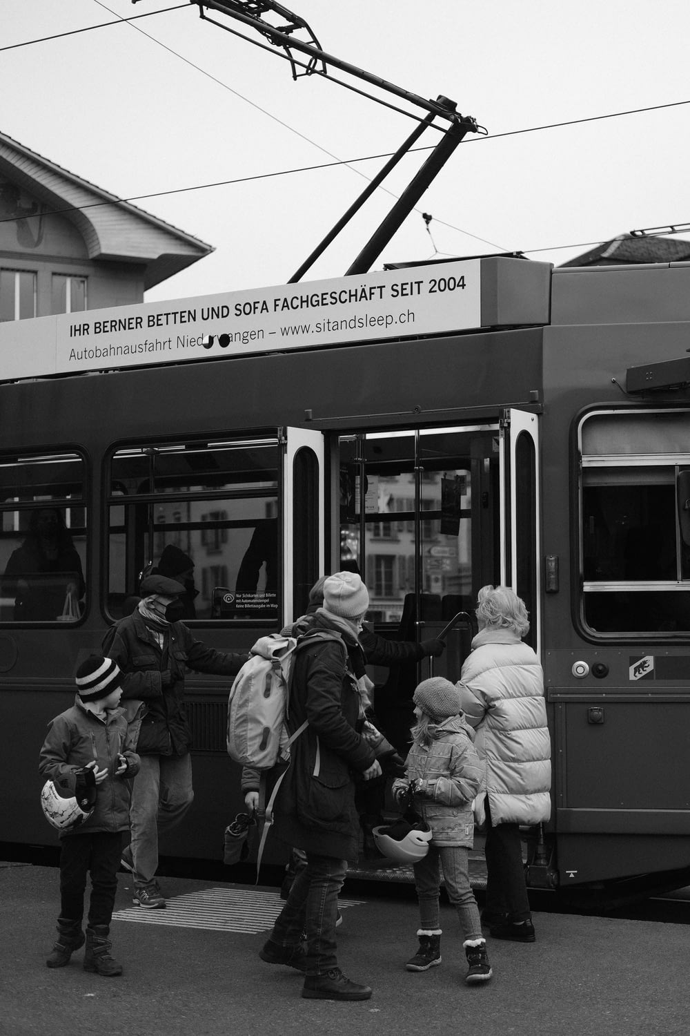 a black and white photo of people boarding a bus
