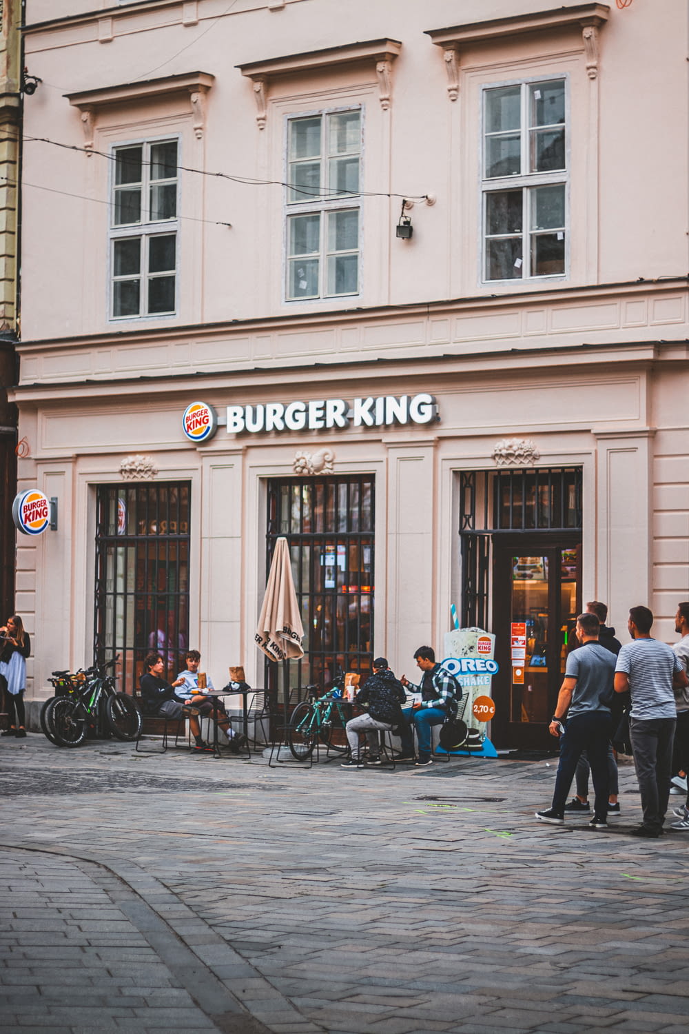 a group of people sitting outside of a burger king restaurant