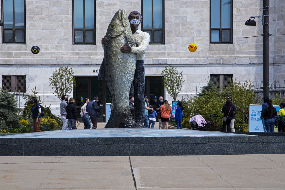 una statua di un uomo che tiene un pesce di fronte a un edificio