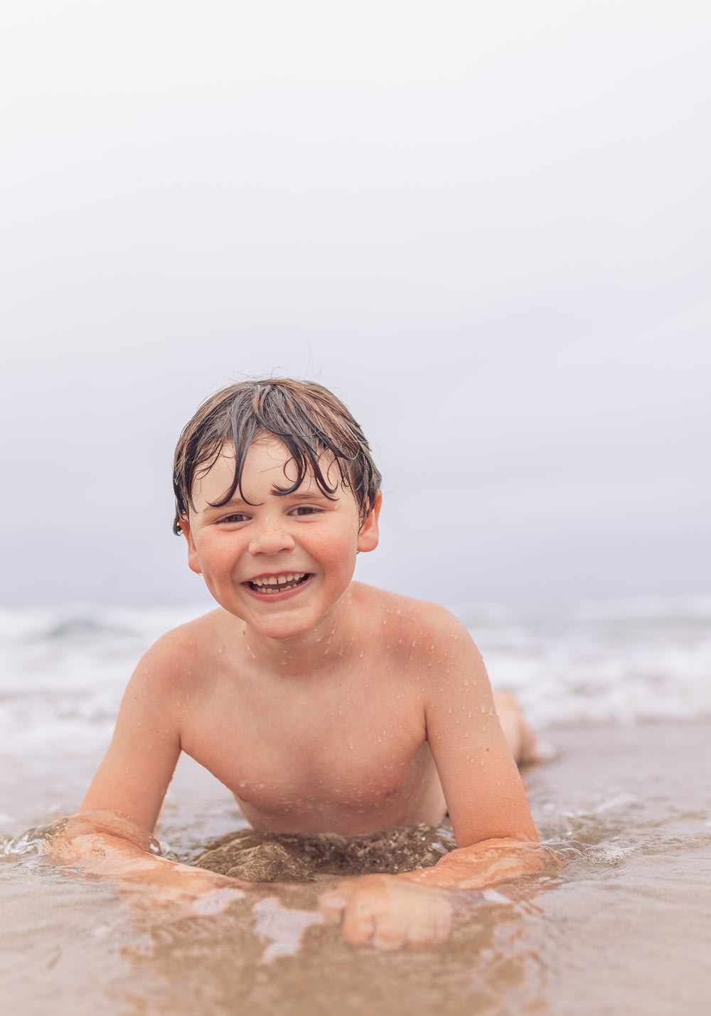 a young boy is playing in the water at the beach