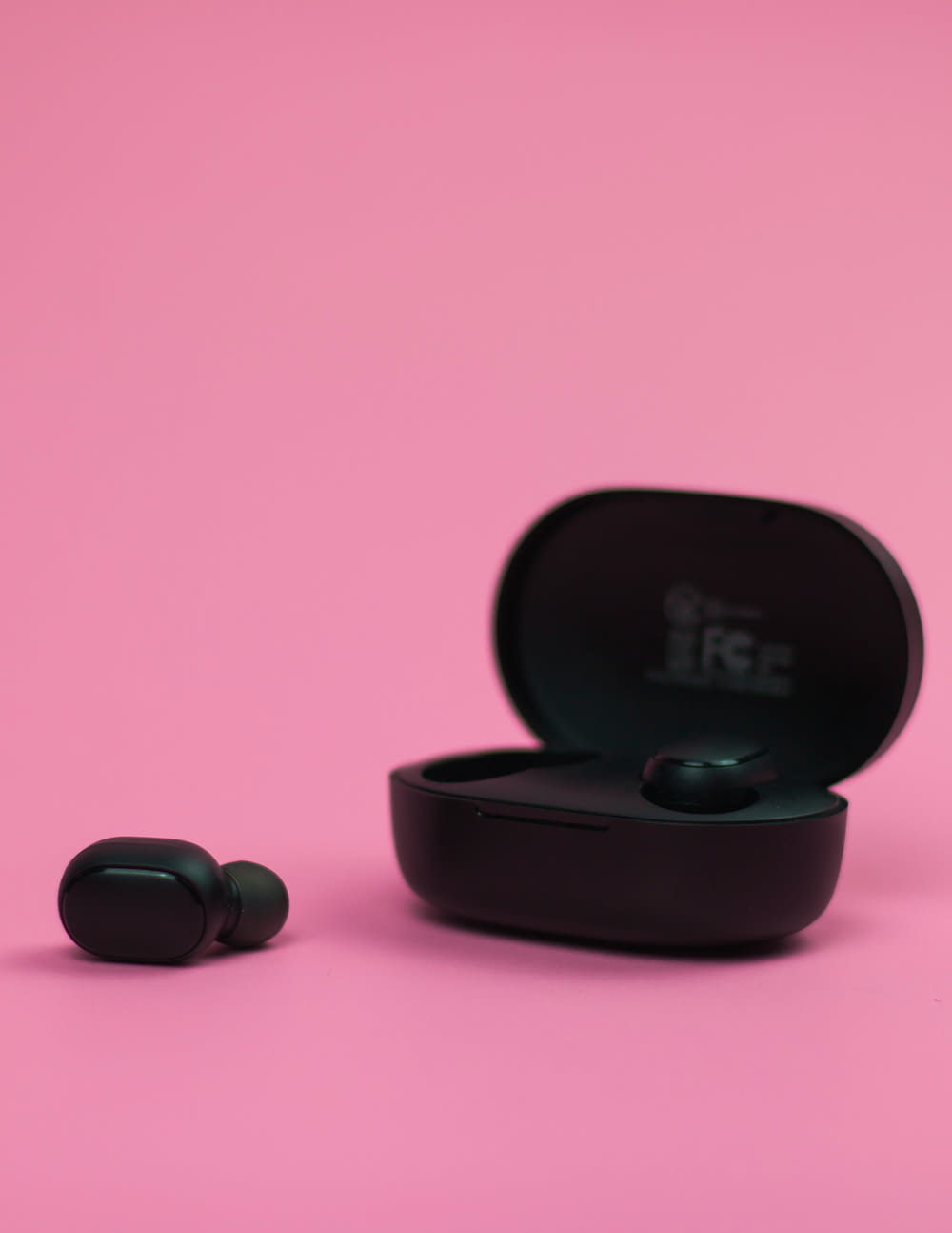 a pair of ear buds sitting on top of a pink surface