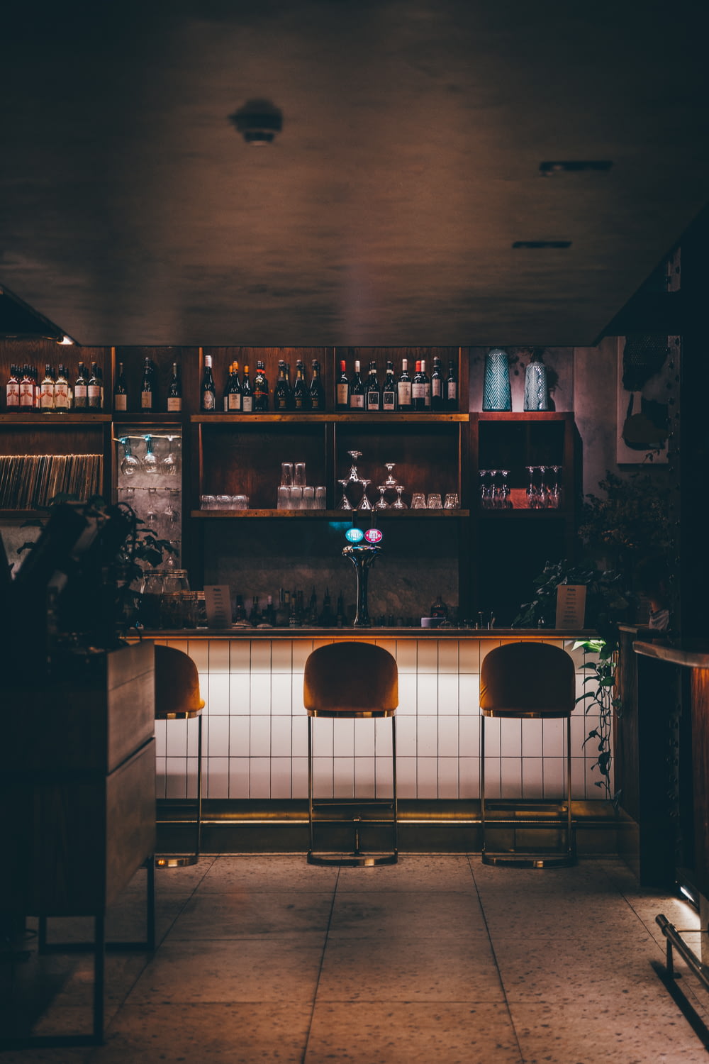 a dimly lit bar with chairs and shelves