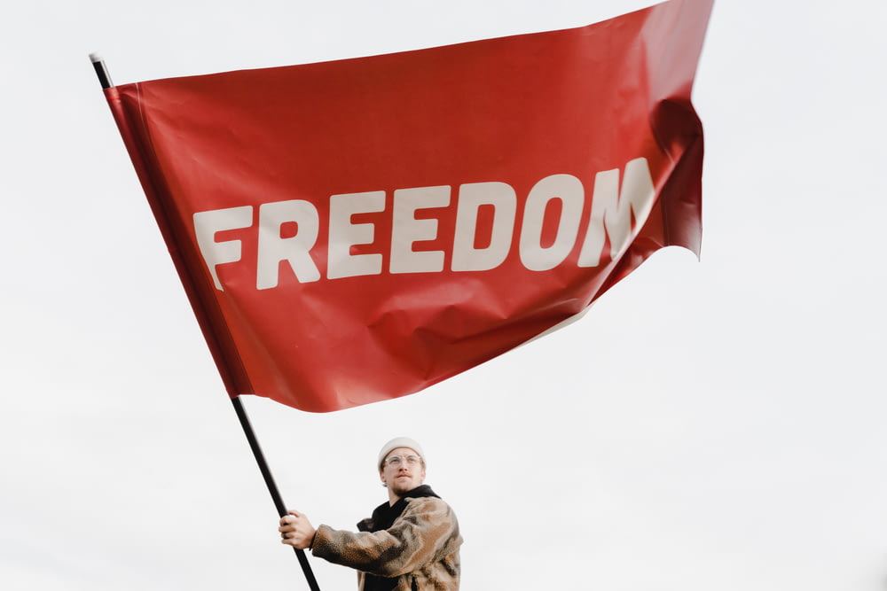 자유라는 단어가 적힌 붉은 깃발을 들고 있는 남자