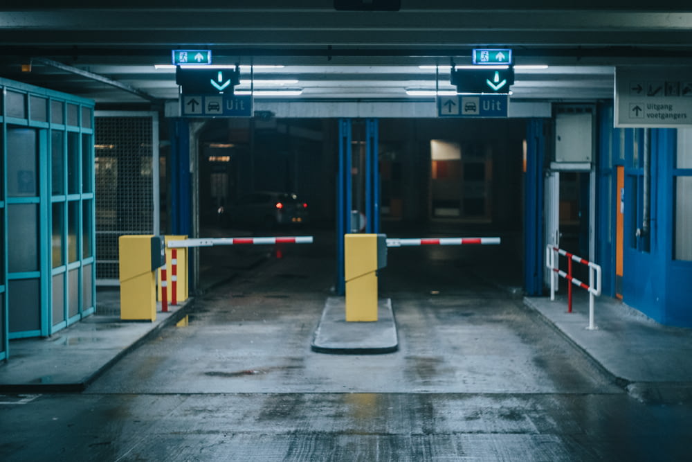 an empty parking garage with blue doors and yellow barriers