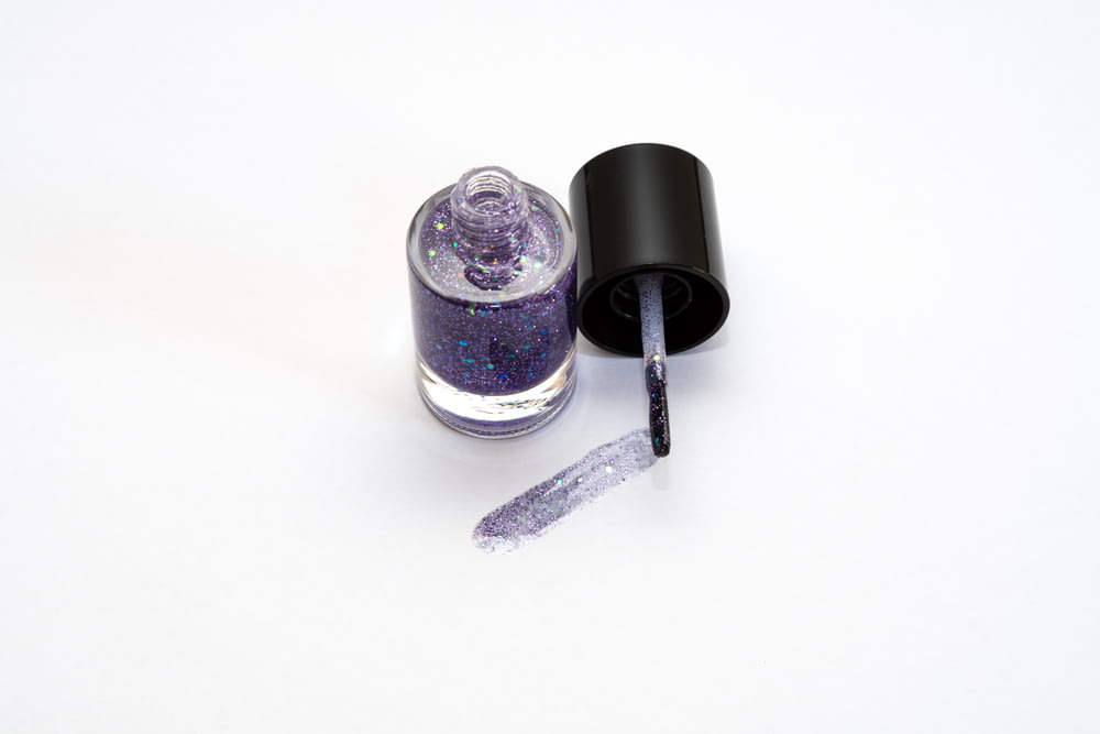 a bottle of purple glitter next to a black bottle