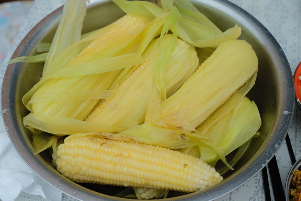 a metal bowl filled with corn on the cob