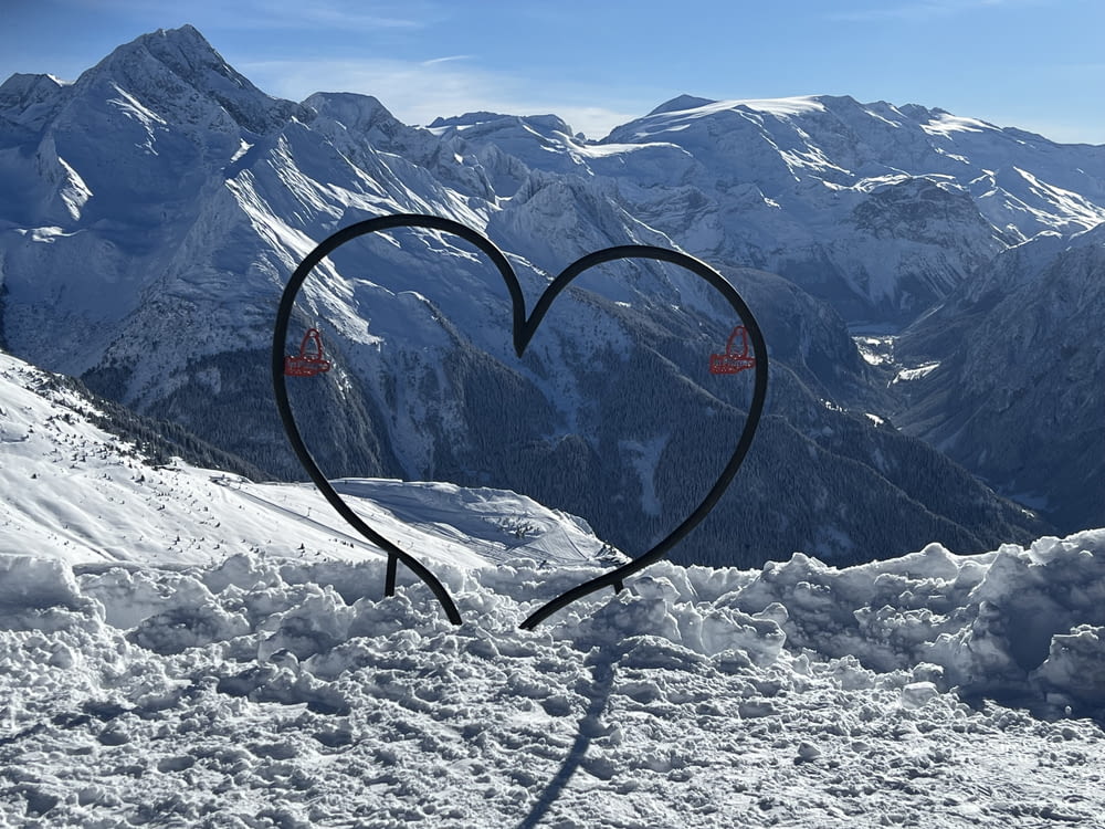 a heart - shaped object in the snow with mountains in the background