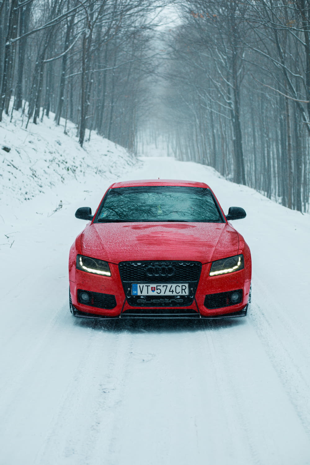 Ein rotes Auto fährt eine schneebedeckte Straße hinunter
