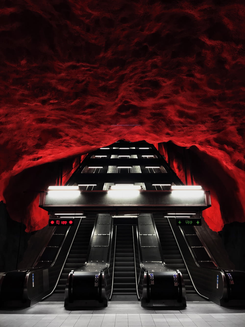 an escalator in a subway station with red walls