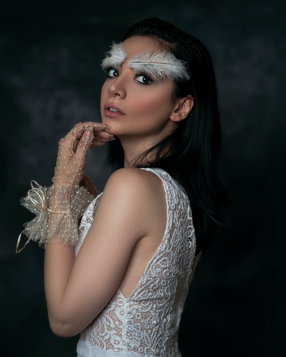 Una mujer con un vestido blanco con plumas en la cabeza