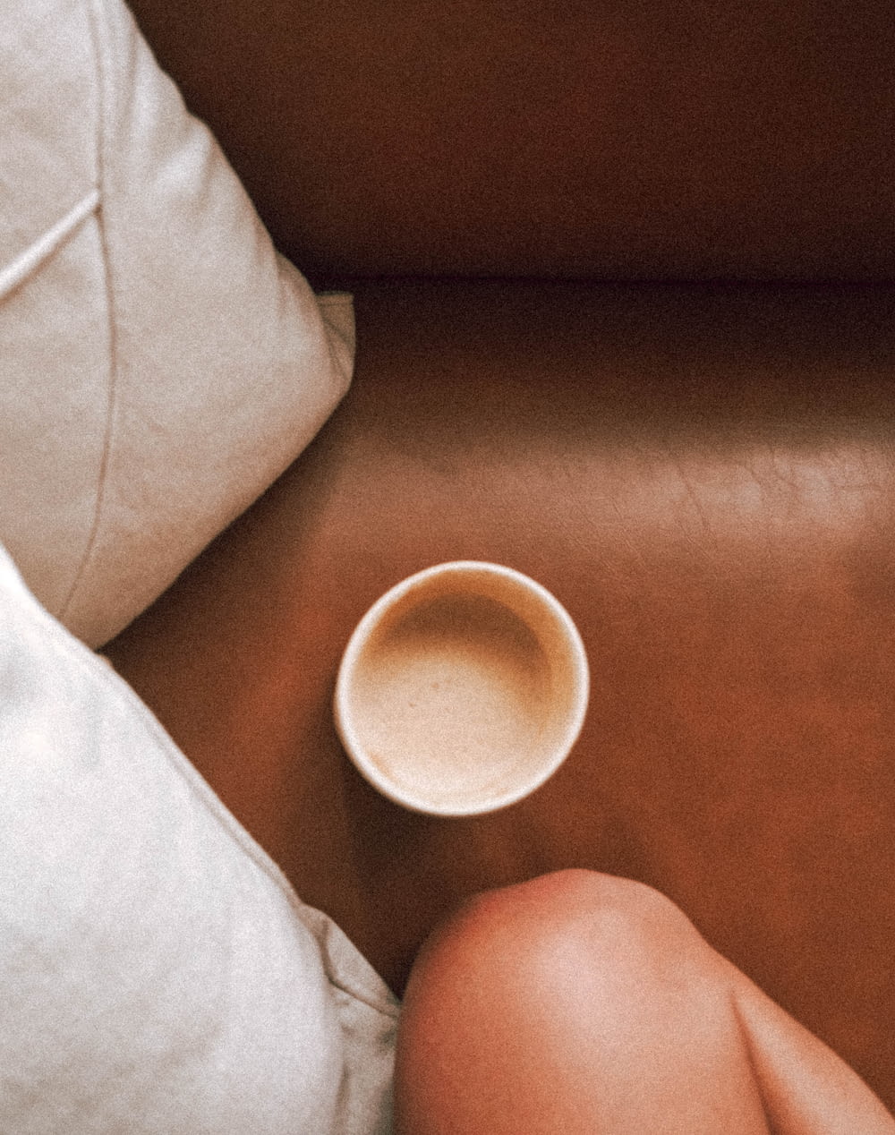 a woman sitting on a couch next to a cup of coffee