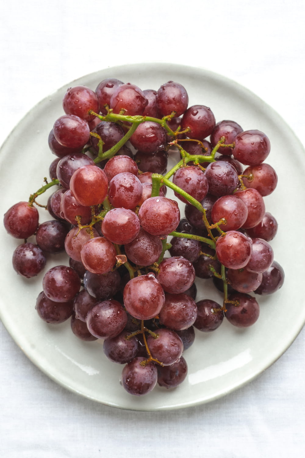 a white plate topped with grapes on top of a table