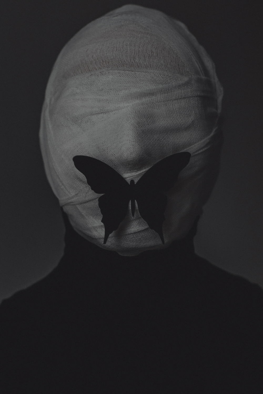 a black and white photo of a person with a butterfly on their face