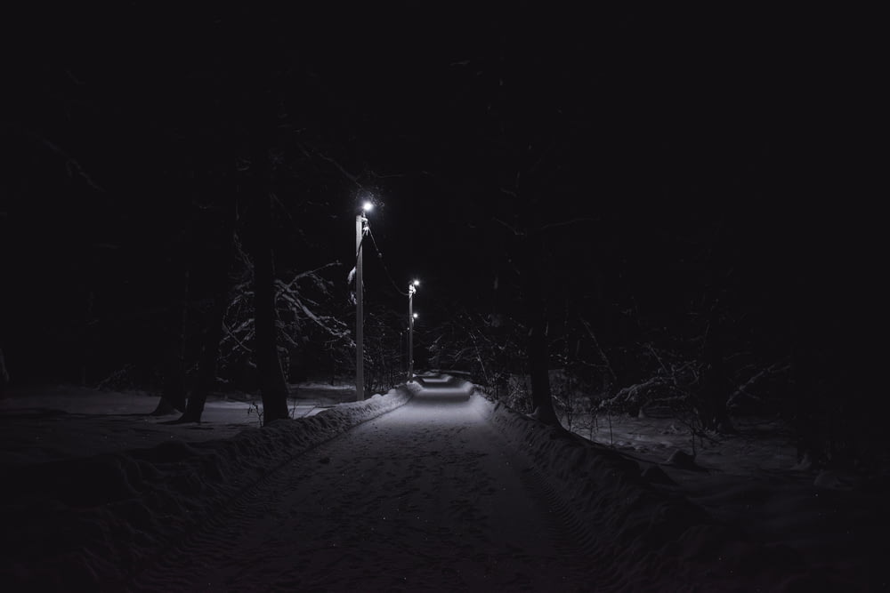 a snowy path at night with a street light in the distance