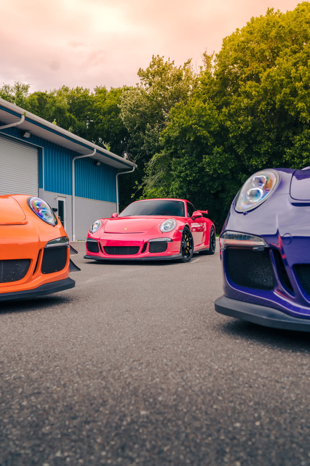 three different colored sports cars parked in front of a garage