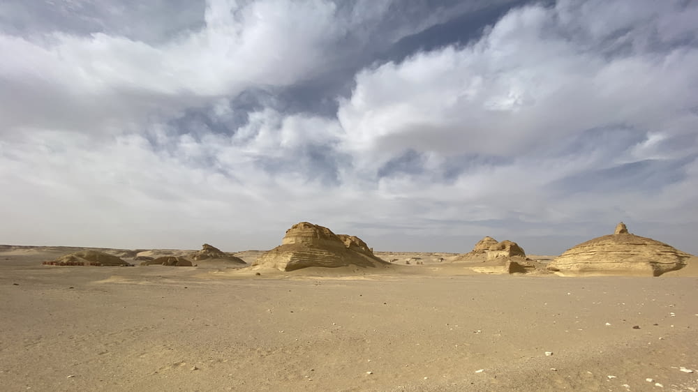 a desert landscape with rocks and sand under a cloudy sky
