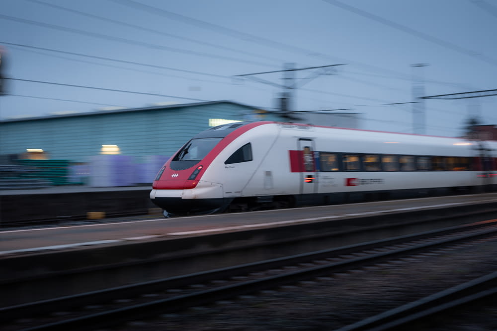 Un treno rosso e bianco che viaggia lungo i binari del treno