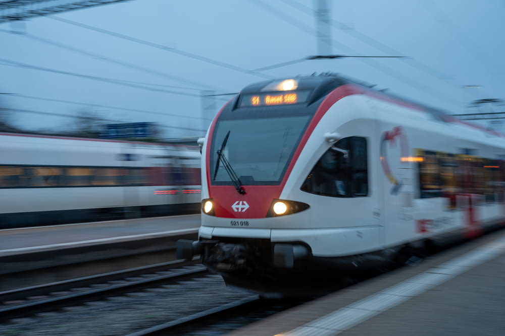Un treno rosso e bianco che viaggia lungo i binari del treno