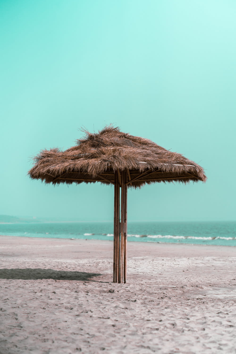 a straw umbrella on a sandy beach near the ocean