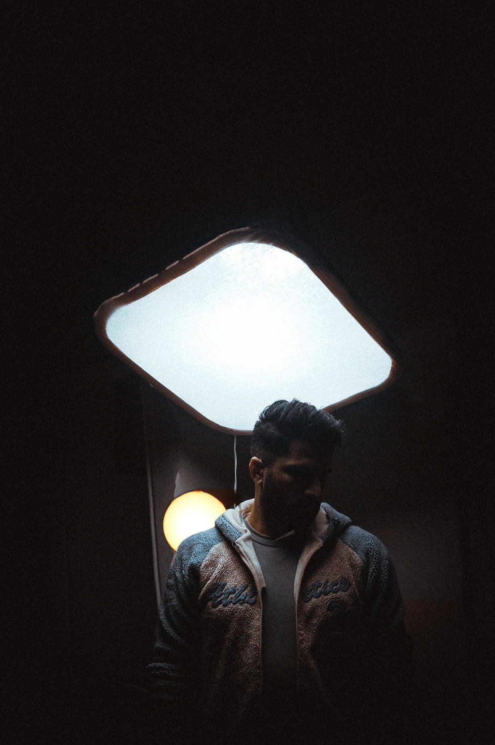 a man standing in front of a light in a dark room