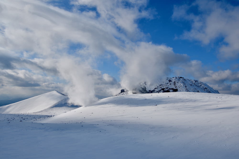 a snow covered mountain with a cloud of smoke coming out of it