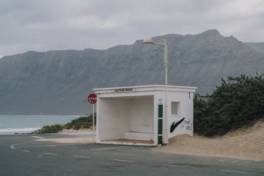 an outhouse on the side of a road near the ocean