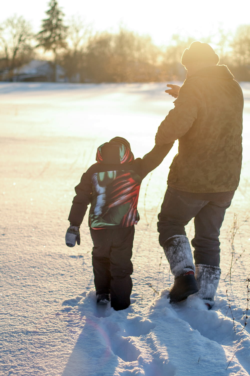 a man holding the hand of a small child in the snow